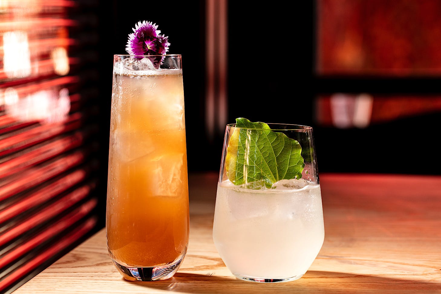 A tall orange cocktail sits beside a short lemonade-hued cocktail at Bedford Soda & Liquor.